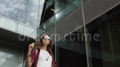 梦想中的女孩戴着太阳镜站在现代建筑附近